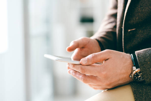 istock Young elegant businessman with wristwatch holding smartphone while texting 1185081095