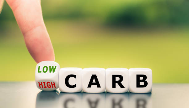 la mano gira un dado e cambia l'espressione da "alto contenuto di carboidrati" a "basso contenuto di carboidrati". - dieta a basso contenuto di carboidrati foto e immagini stock