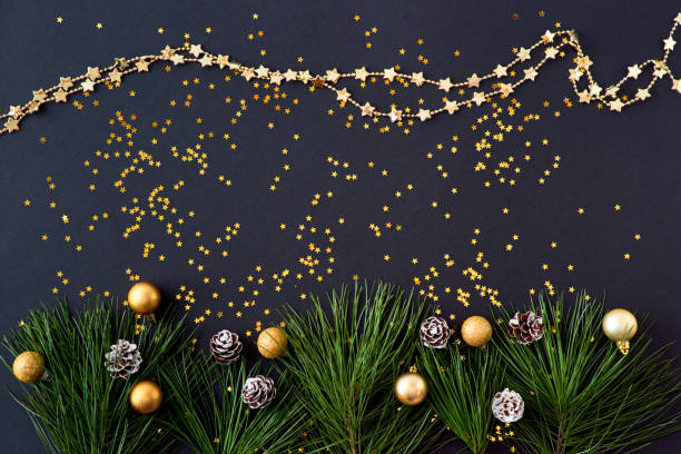 istock Flat lay christmas border with pine branches and golden confetti on a dark background 1185085490