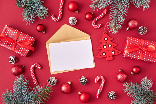 istock Mockup white greeting card and envelope with red christmas balls, spruce branches and gift box on a red background 1185085518