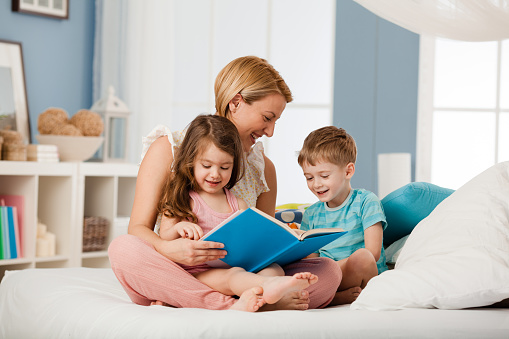 Mother reading book to her children before bed time
