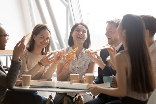 istock Cheerful multicultural team workers laugh share lunch meal eating pizza 1185095758