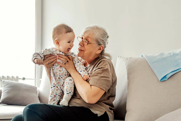 Family Playtime Grandmother holding little grandson in the room at home. Senior woman hold little baby cute smiling. Happy grandmother with her grandchild in home. 2 5 months photos stock pictures, royalty-free photos & images