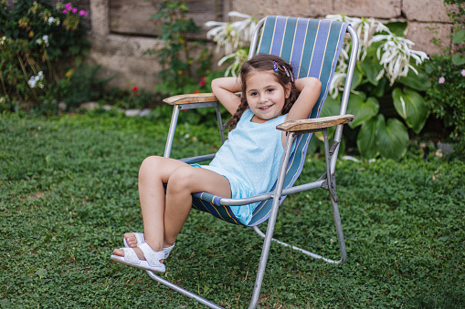 Beautiful little girl taking a break on deckchair after playing with her sister.