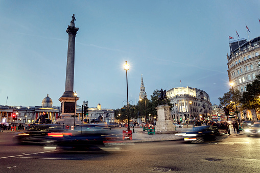 Traffic and crowd of people at Trafalgar Square in London at dusk