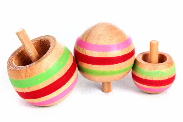 istock Three wooden tippe tops on white background 1185119035