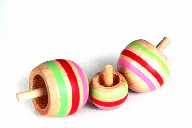 istock Three wooden tippe tops on white background 1185119048