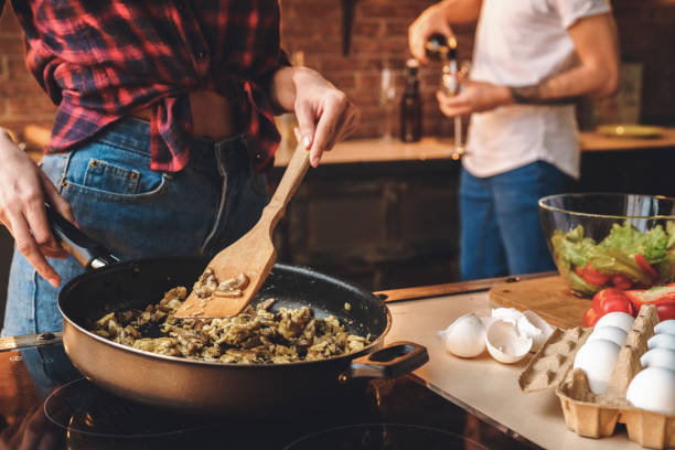 istock Date rejoicing. Woman cooking, man pours wine 1185122202