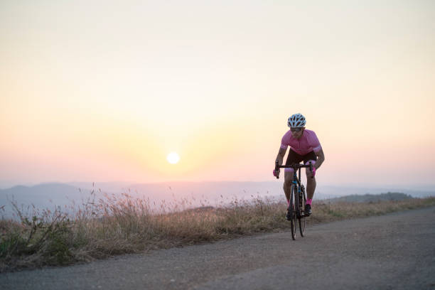 Athlete on racing bike outdoors at sunset.