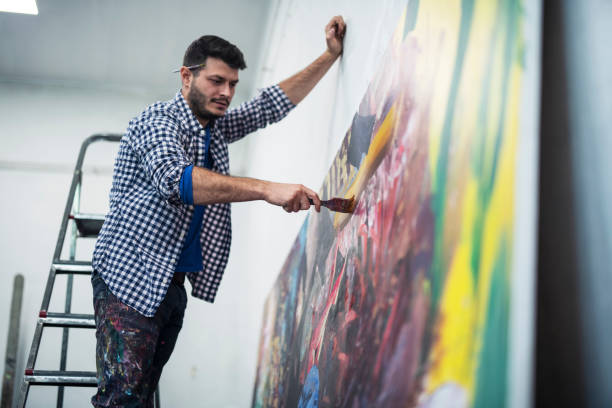 istock Young Artist working on big painting 1185122261