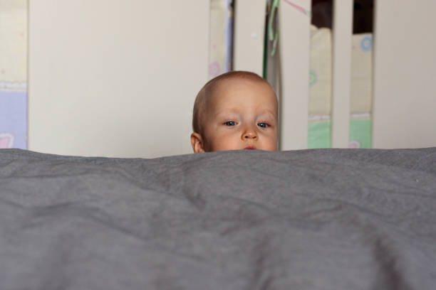 istock Curiosity. A curious baby's face peeks out over the bed. Education, interest, emotions. Face close up. 1185122613
