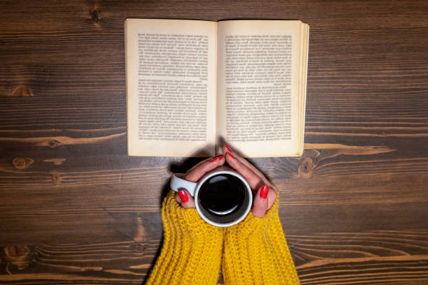 istock Shot from above of woman drinking coffee while reading a book 1185122676