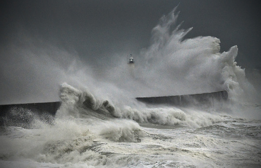Mighty waves in the English channel overwhelm Newhaven harbour lighthouse, East Sussex. UK\nColour image but looks monochrome