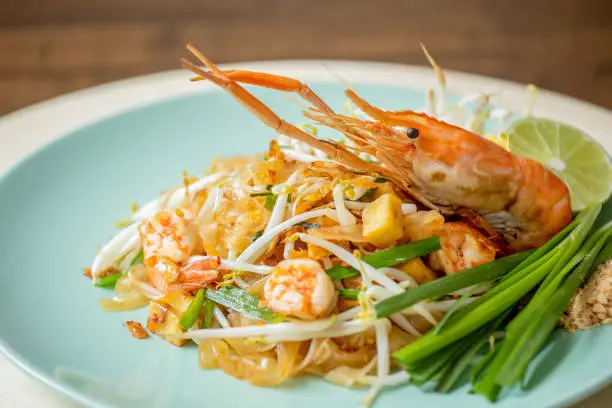 Photo of Close up of delicious hot fresh Pad Thai garnished with big shrimp