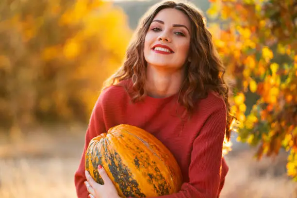 Portrait of a beautiful young caucasian woman holding a pumpkin.