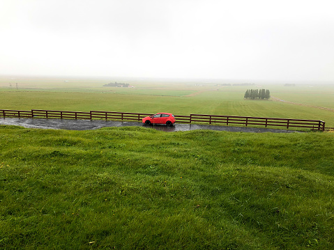 Iceland Road Trip: A red car parked on a wet road in a grassy area near Hellisholar in South Iceland.