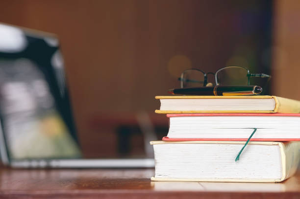 istock Stack of old boos on wooden table with laptop in library. Copy space. 1185130944