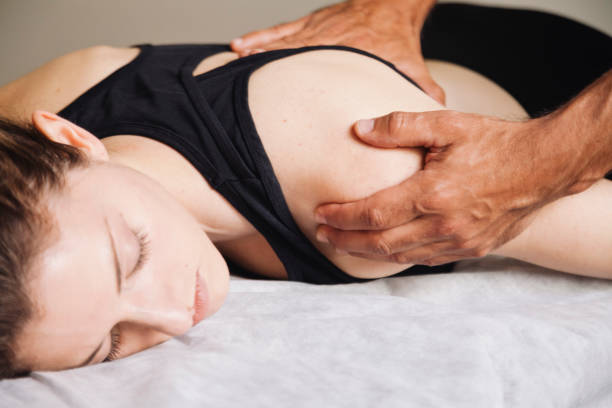istock rehabilitation therapy. Hands treating a young woman's shoulder 1185133208
