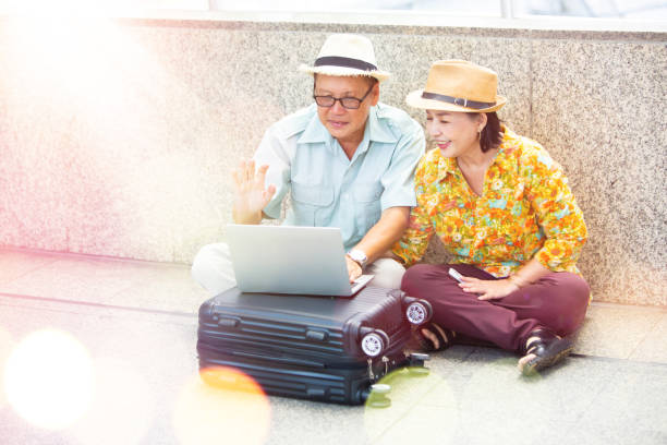 concepto de viajes y turismo. active happy senior pareja sentada en el piso con videollamada portátil - couple walking old middle fotografías e imágenes de stock