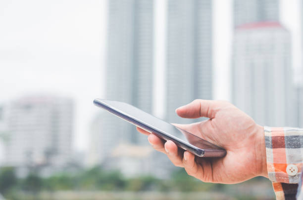 istock close up handsome man using hand typing smartphones and touch screen working search with app devices outdoor in city with sunrise and building background. 5G technology connecting the world. 1185147330