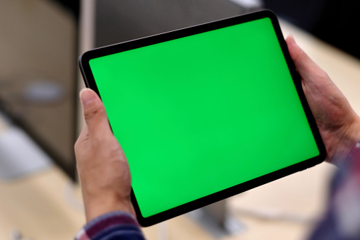 Sobre el hombro de un hombre sosteniendo la tableta de pantalla verde pc en la oficina. photo