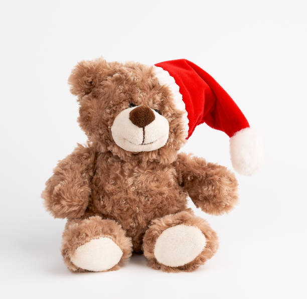 cute brown teddy bear in a red christmas hat sits