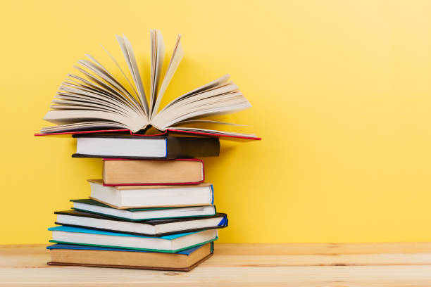 istock Simple Simple composition of many hardback books, unprocessed books on a wooden table and a yellow background. back to school. Copy space. Education. 1185157086