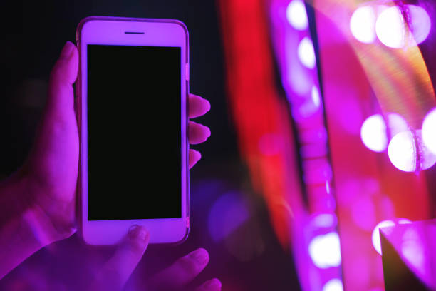 istock Woman's hand showing smartphone screen in neon red and violet lights 1185162084