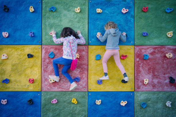 duas meninas que penduram em porões na parede de escalada - climbing wall rock climbing holding reaching - fotografias e filmes do acervo