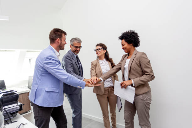 istock Group of four multiethnic cooworkers at the office holding hands 1185166525
