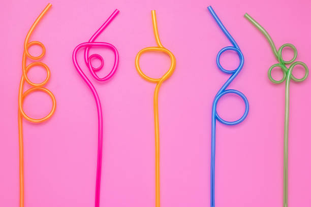 istock Plastic spiral multicolor tubes on pink paper card. Abstract colorful background of curved cocktail straws. Laconic design. Concept of fun mood. Modern style. 1185169708