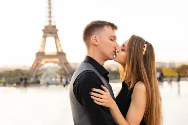 Photo of Couple kisses near the Eiffel Tower. From Paris with love. Romantic date or honeymoon concept