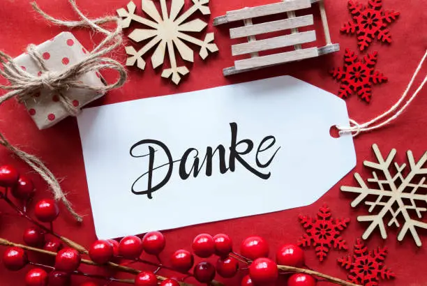 One Label With German Calligraphy Danke Means Thank You. Bright Red Christmas Deocration Like Sled, Present And Snowlfakes