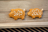 Pour feliciter 2020, gingerbread pig with year 2019 is followed by pig with 2020 sign, wooden background, Christmas stil life