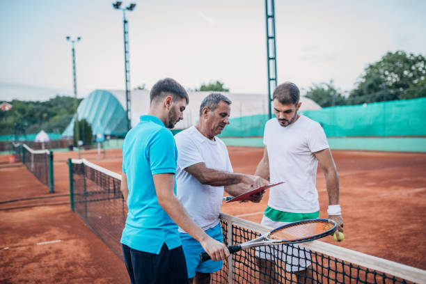 coach unterrichtet männer tennisunterricht - tennis active seniors healthy lifestyle senior men stock-fotos und bilder