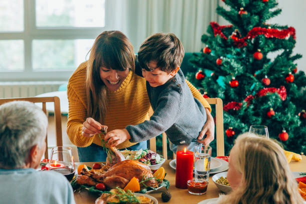 ロースト七面鳥の足を持ちながら楽しんでいる幸せな母親と彼女の息子 - holiday season turkey food ストックフォトと画像