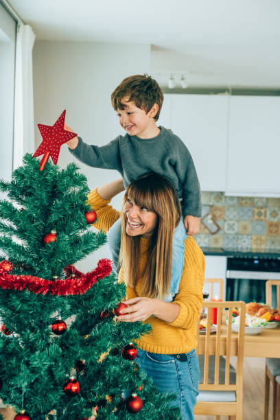 matka i syn kładąc gwiazdę na choince - christmas christmas tree angel decoration zdjęcia i obrazy z banku zdjęć