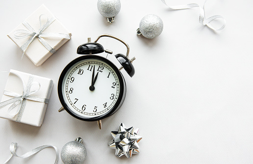 Flat lay composition with alarm clock and Christmas decorations on white background.