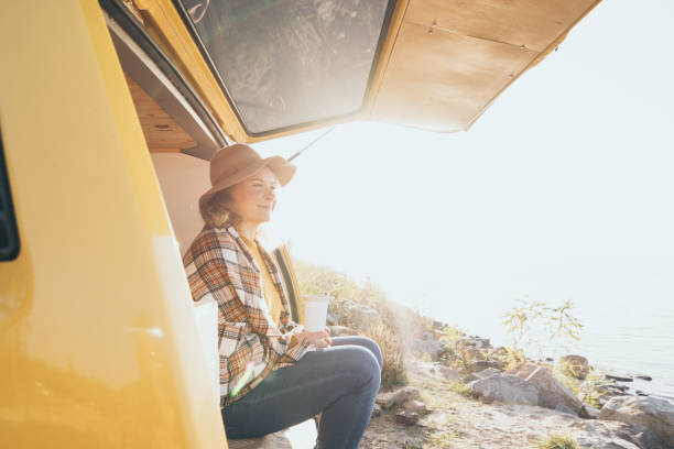 Young blonde Caucasian woman relaxing in her campervan at sunset stock photo