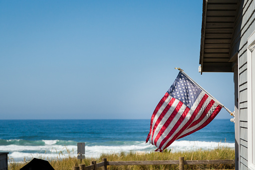 A beautiful oceanfront property with a classic American flag on the side of it with the coastline in the background