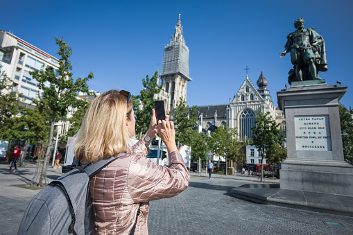 A woman tourist takes pictures of the sights on her mobile phone.