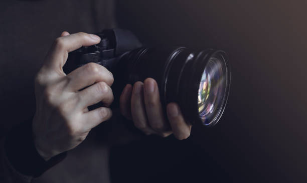 istock Young Photographer Woman using Camera to Taking Photo. Dark Tone. Selective Focus on Hand 1185206737