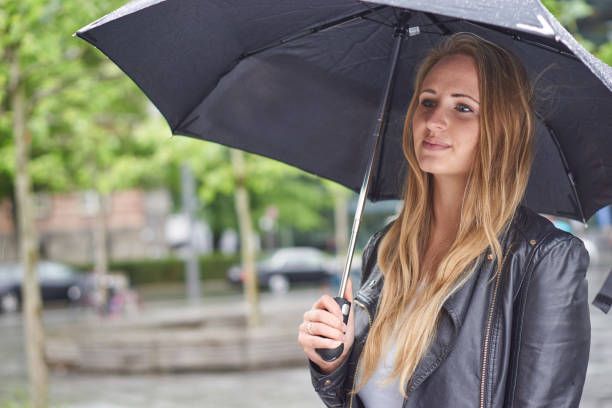 istock Cute blonde with umbrella in rain 1185208005