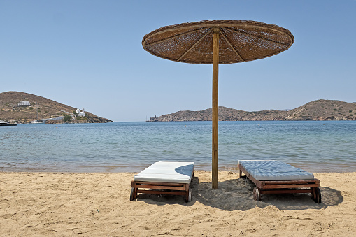 Umbrella and sunbeds on sand in front of the sea cost