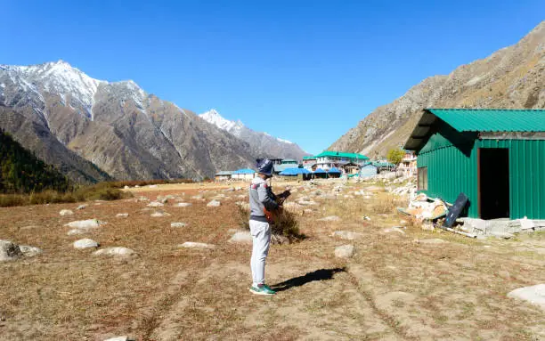 A solo traveler of Indian ethnicity and hobbyist  musician playing music with guitar on mountain valley. Alone in the silence of Himalayan mountain and sound of guitar strings. Summer music Inspiring environment in outdoors. Sangla Valley, Himachal Pradesh, India, South Asia.
