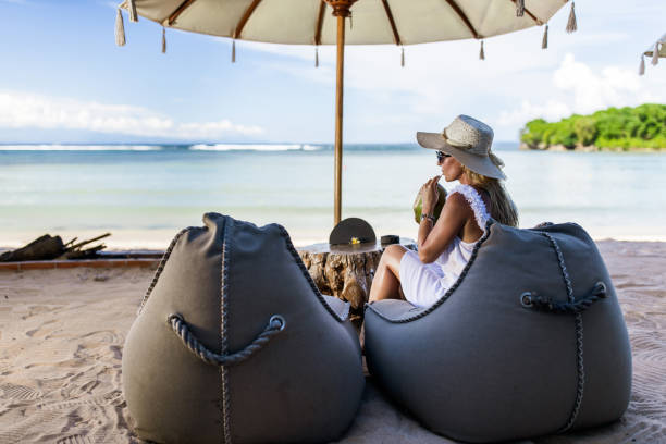 Young woman drinking coconut on the beach.
