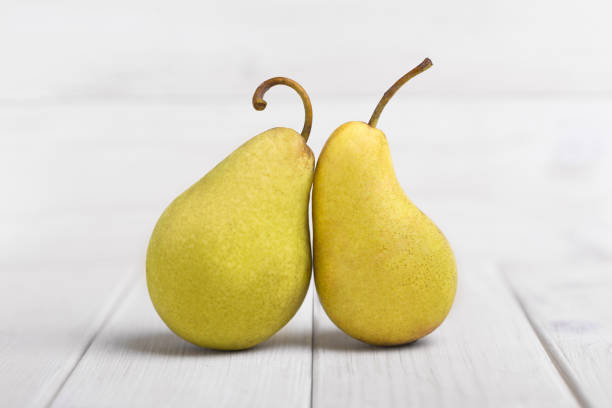 Two Fresh yellow Pears on a white wooden table Two Fresh yellow Pears on a white wooden table perfect pear stock pictures, royalty-free photos & images