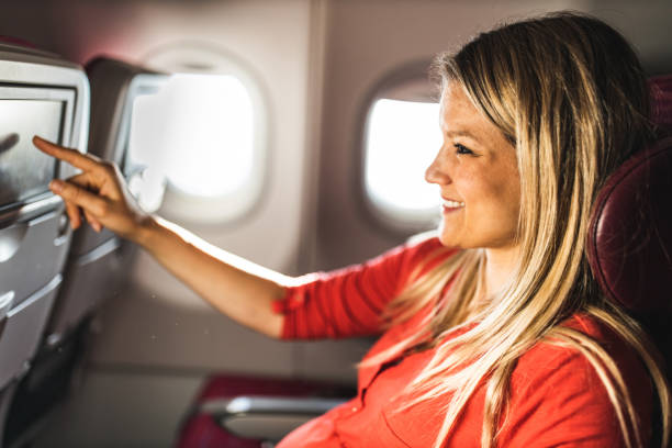 istock Young happy woman using touch screen during her flight by plane. 1185214790