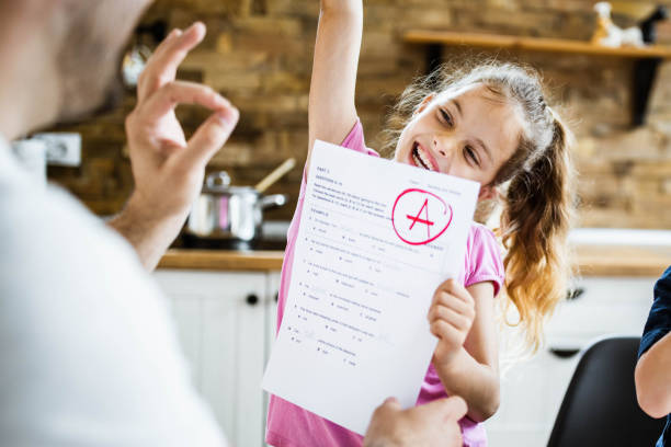 Yay daddy, I've got an A on my exam! Happy little girl feeling satisfied while showing her father an A grade on her test. good grades stock pictures, royalty-free photos & images