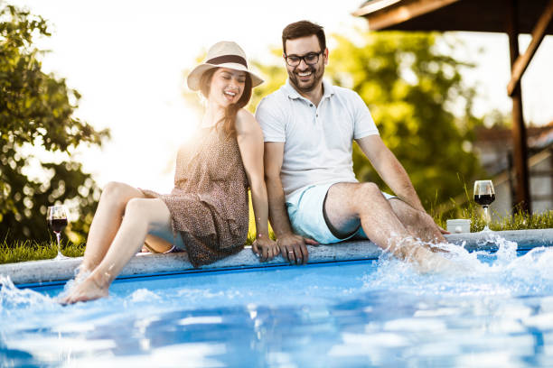 istock Happy couple having fun while splashing water in the pool. 1185217083